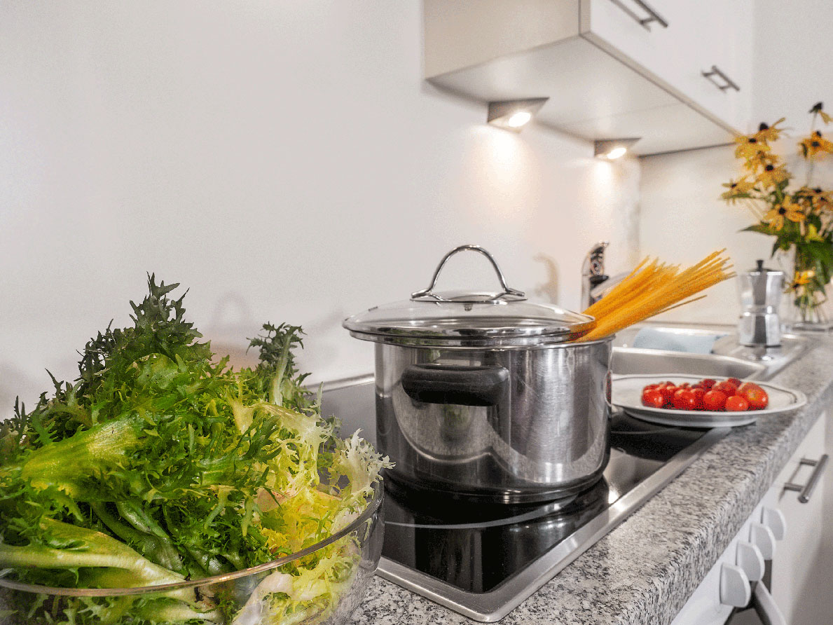 Ein kochender Kochtopf mit Nudeln und ein Salat im Appartement Helm